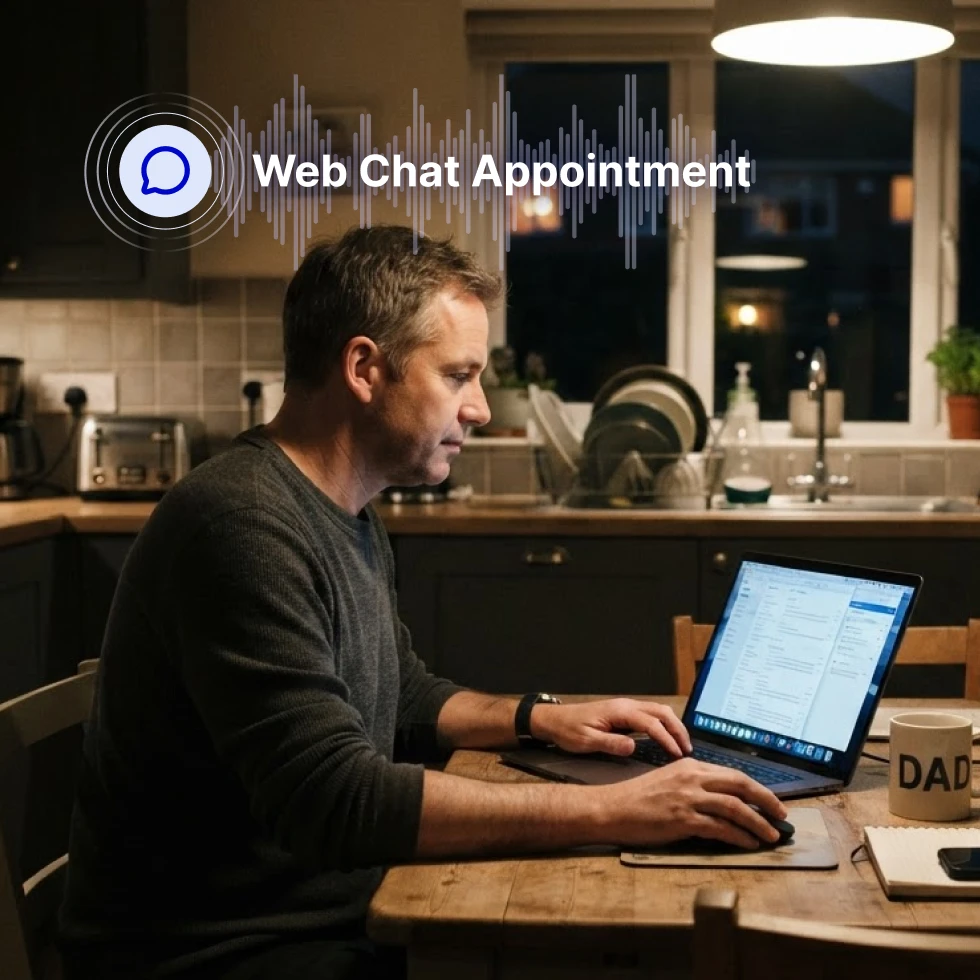 Man in dark sweater sitting at a kitchen counter in the evening, working on laptop displaying web application interface. Overhead pendant light and kitchen sink visible in background. Overlaid chat bubble icon with sound wave graphic and white text reading "Web Chat Appointment."